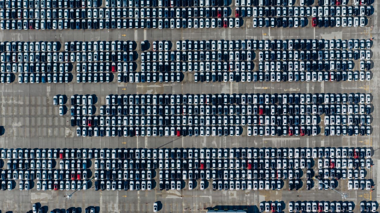 Rows of new vehicles staged in a distribution yard, seen from the air.